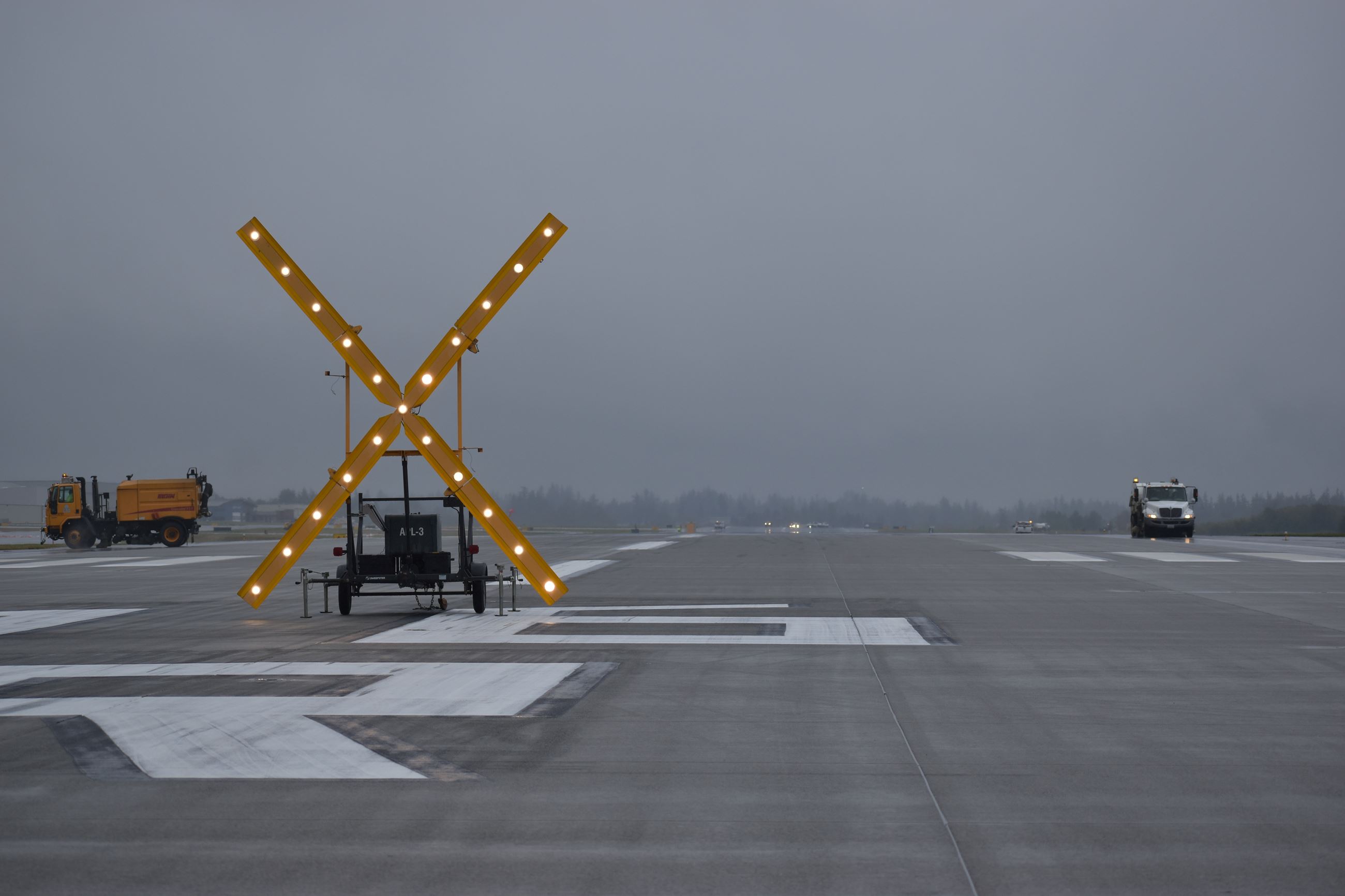 Yellow lighted X to indicate runway is closed under cloudy skies