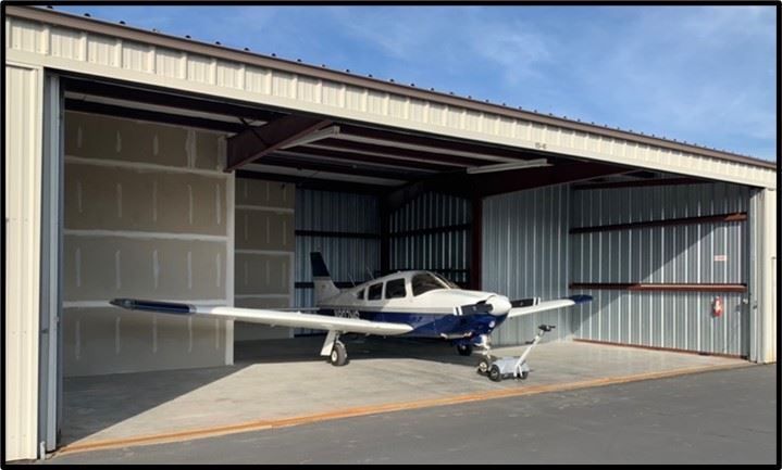 East Condo for sale with doors open and a Piper Arrow III parked inside